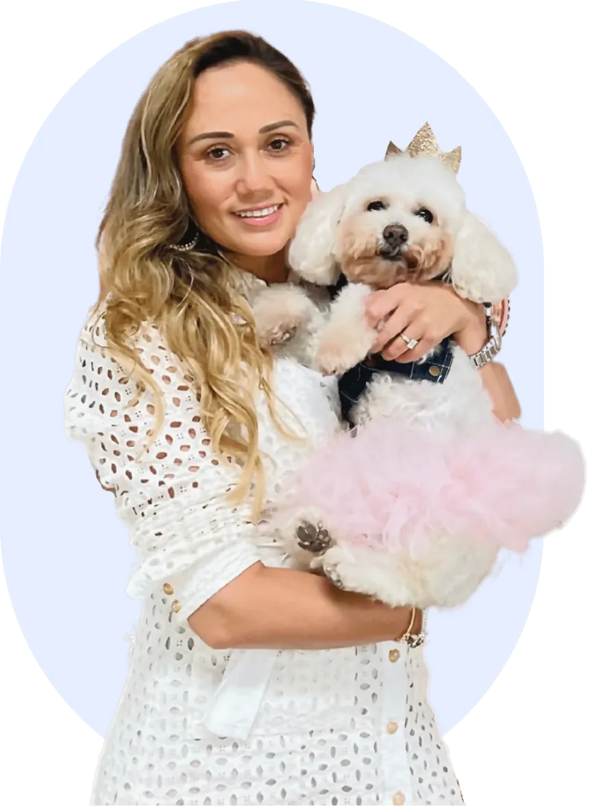 Doggieville MTL owner holding a groomed poodle in a pink tutu